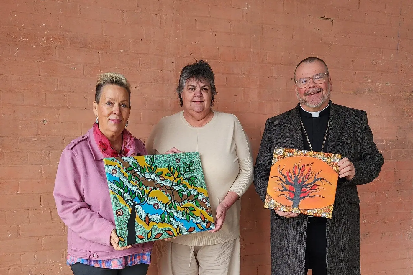 CatholicCare Wilcannia-Forbes CEO Anne-Marie Mioche and director cultural engagement Jane Kemp and Bishop Columba Macbeth-Green, Bishop of the Diocese of Wilcannia-Forbes, award first prize to paintings CatholicCare \\u2013 Families (left) and More Than Meets The Eye (right), by a Parkes artist, in the 2025 CatholicCare Wilcannia-Forbes Aboriginal Art Competition. PHOTO: Supplied