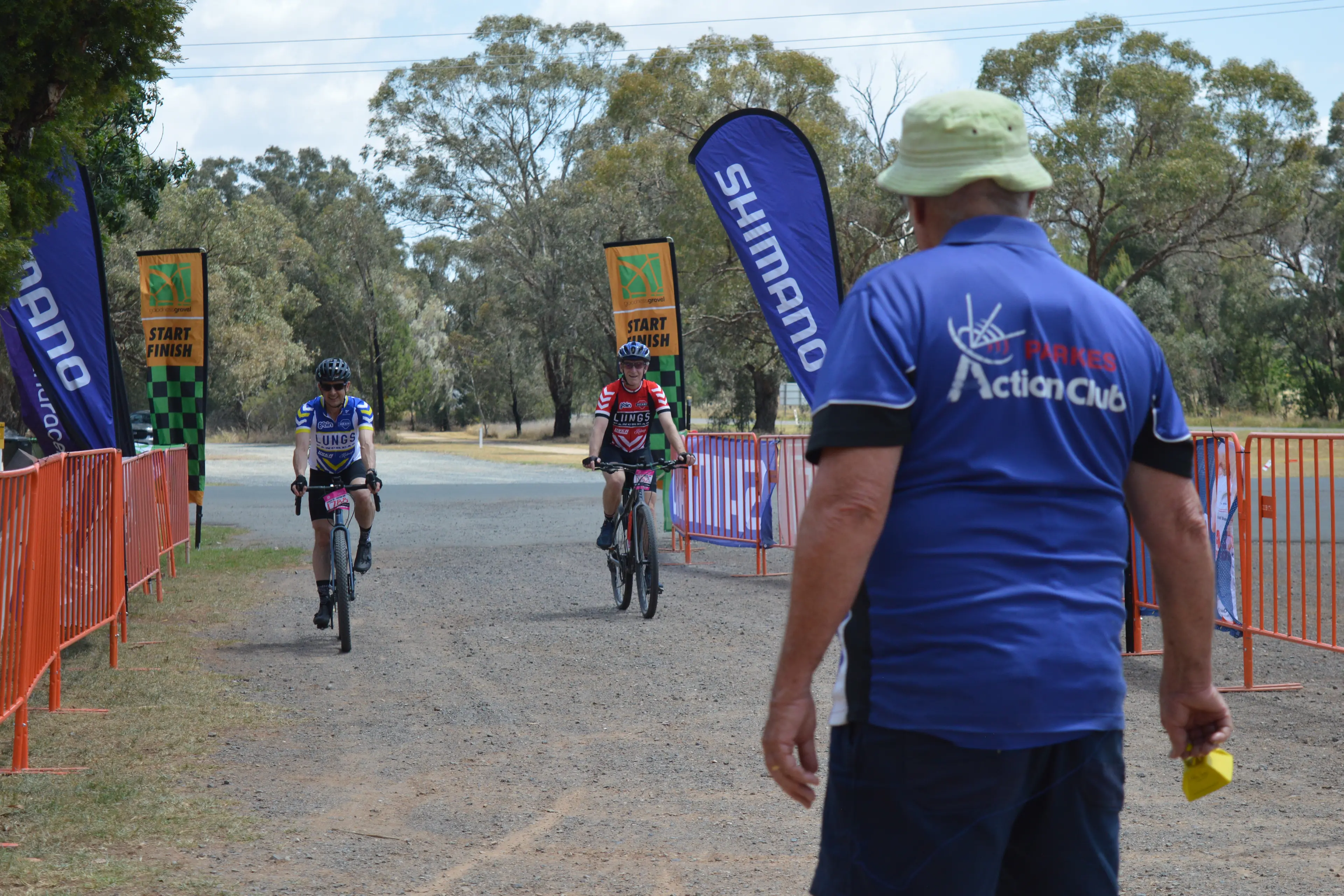 <p>Parkes volunteer Peter Guppy rang the bell to welcome Andrew Parker from Sydney and Les Roberts-Thomson from Moruya at the finish line in the first goodnessgravel cycling event in Parkes. The pair estimated they rode 75km after accidentally taking a detour. PHOTO: Christine Little</p>\\n