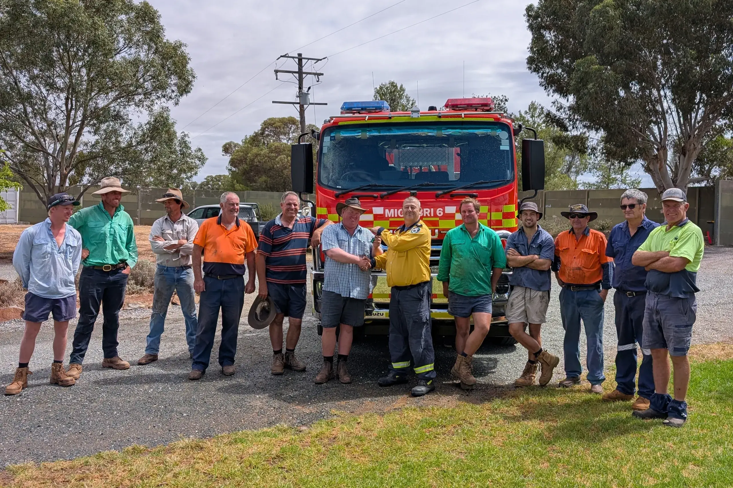<p>Operational officer Scott Baker handing the keys to a new Category 6 truck to captain Shane Green and members of the Mickibri Rural Fire Brigade.</p>\\n